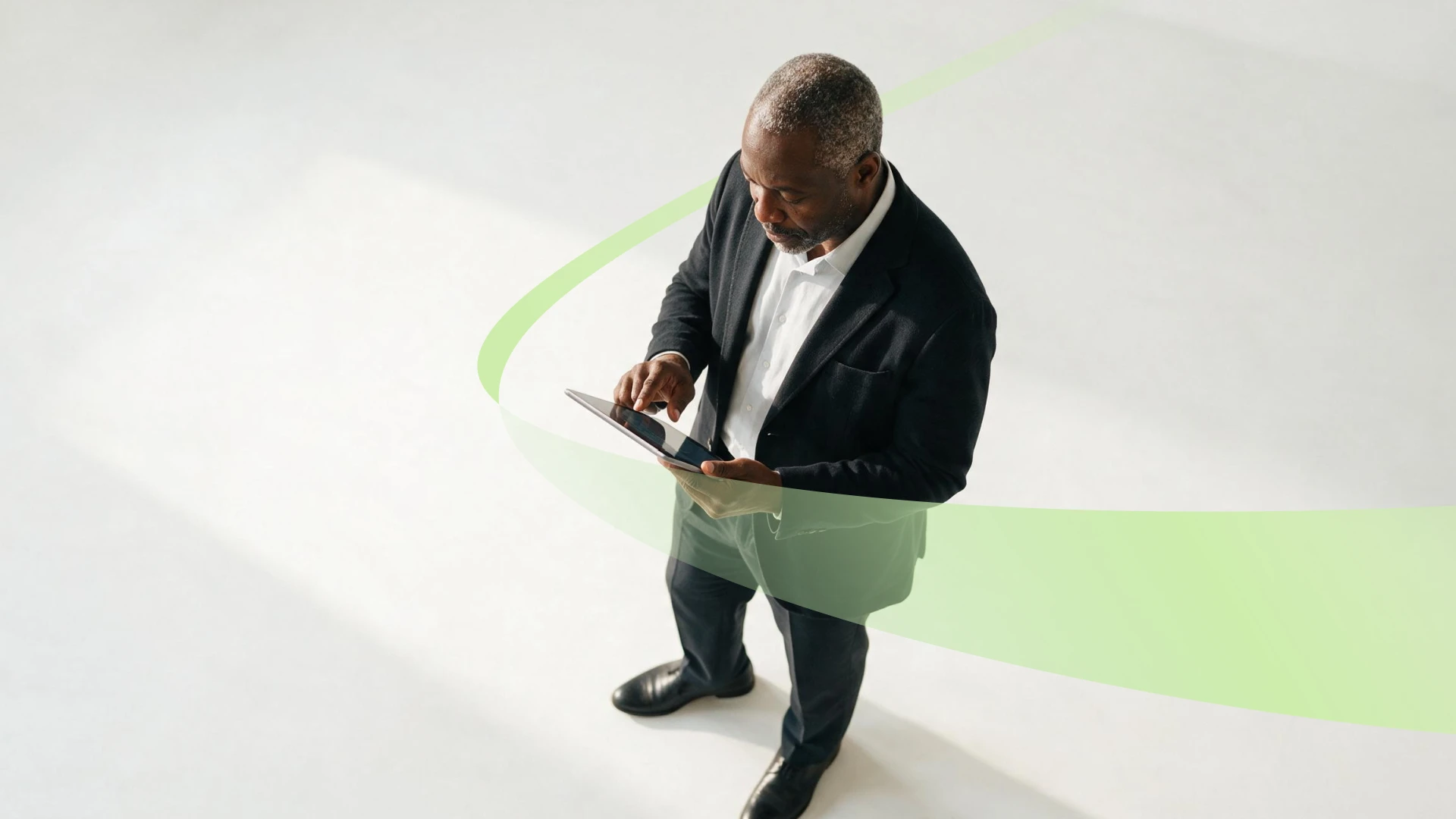 Gestor comercial consultando um tablet, em pé, com uma faixa verde da marca cruzando a cena